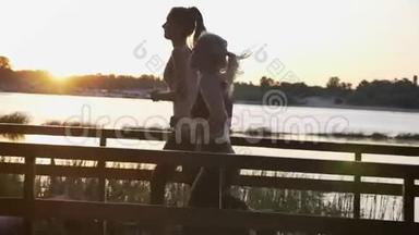 日落时分，两位年轻漂亮的女士在河边公园跑步，减肥，健身模特慢跑，美丽的景色